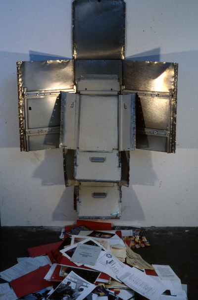 "Purge"  File cabinet and files.  75" x 59" x 50"  1990s  As an act of self exposure, I took apart and mounted my file cabinet, and spilled all of my files on the floor of the gallery.